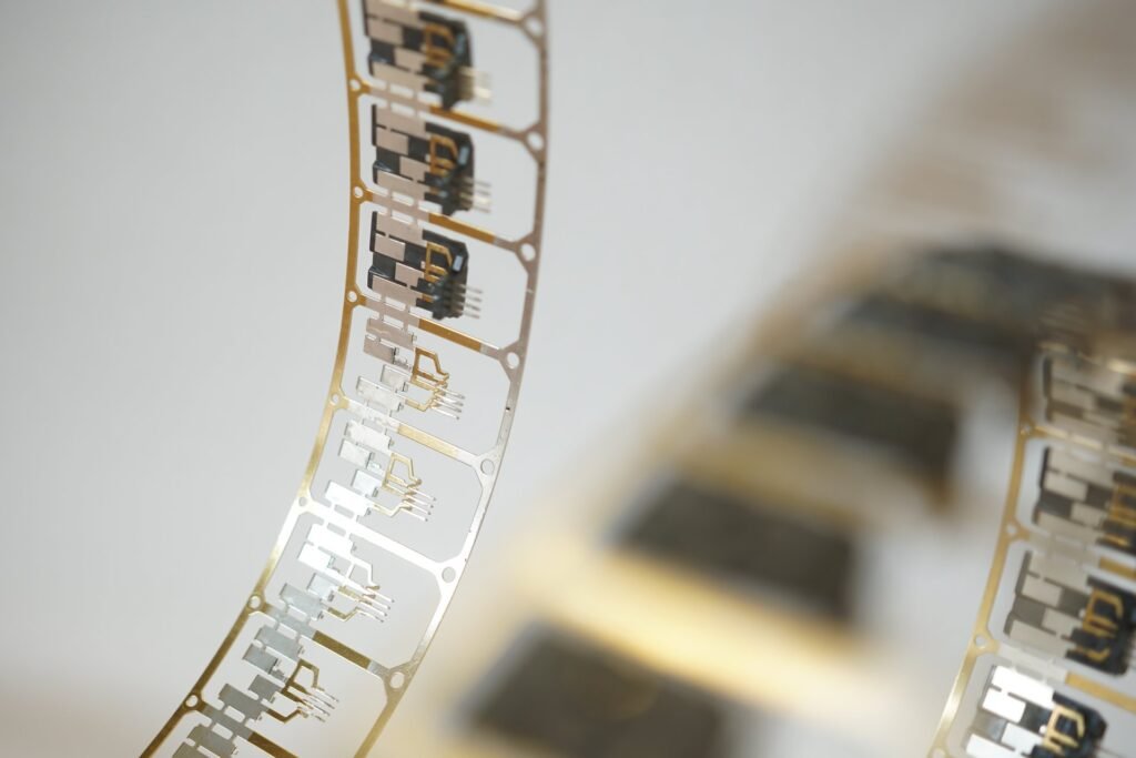 Cinta de componentes electrónicos de precisión, con conectores metálicos dorados y plateados en serie.